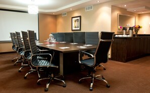 A conference room with a long table, six black leather chairs, a projector screen, and a coffee station. - Park Inn By Radisson Toronto - Markham (Markham)