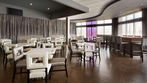 A spacious restaurant with high ceilings, modern lighting, and a mix of booth and table seating.