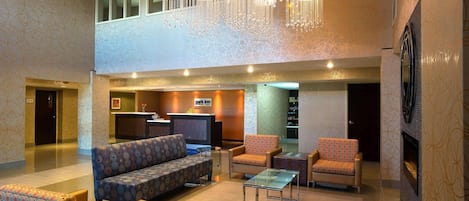 A hotel lobby with a reception desk, seating area, and a television.