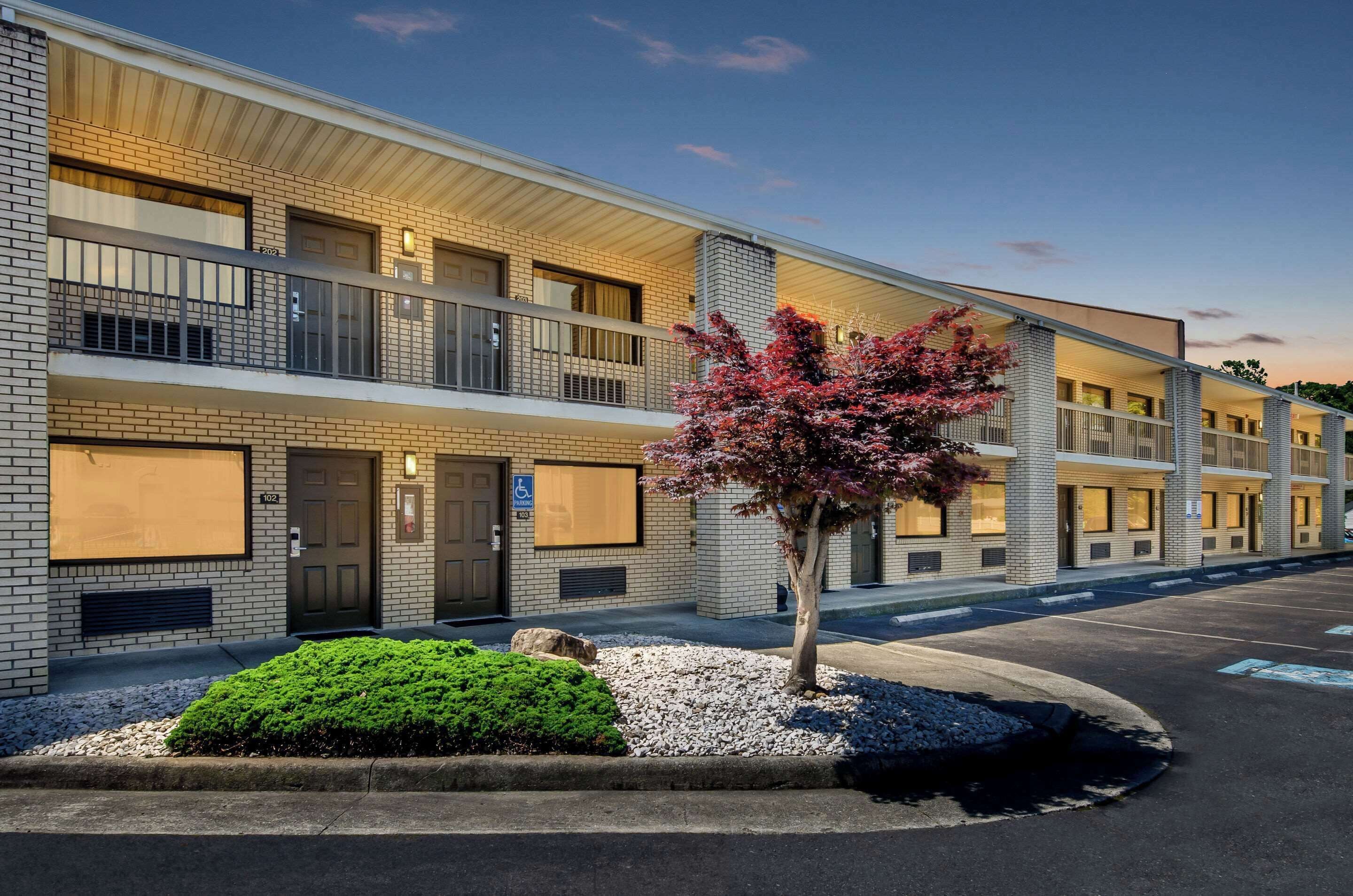 A multi-story hotel with a brick facade, balconies, and a parking lot.