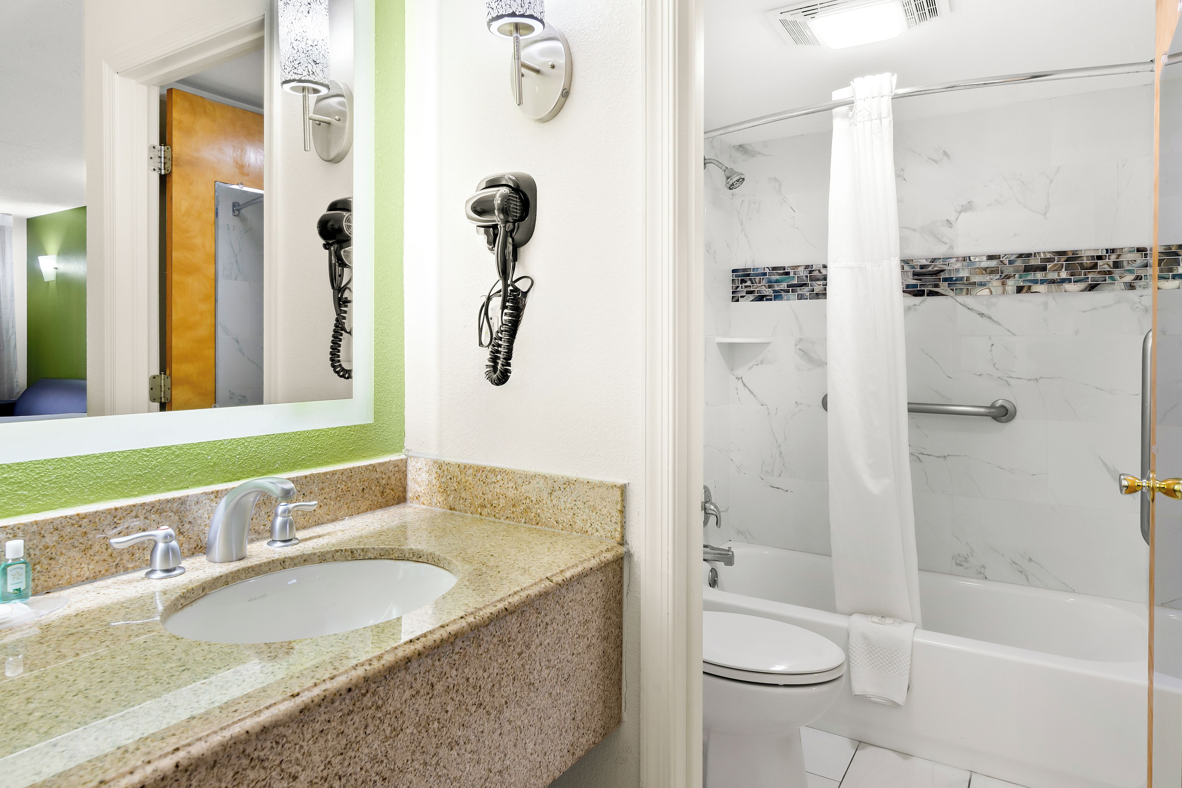 A bathroom with a sink, mirror, and shower.
