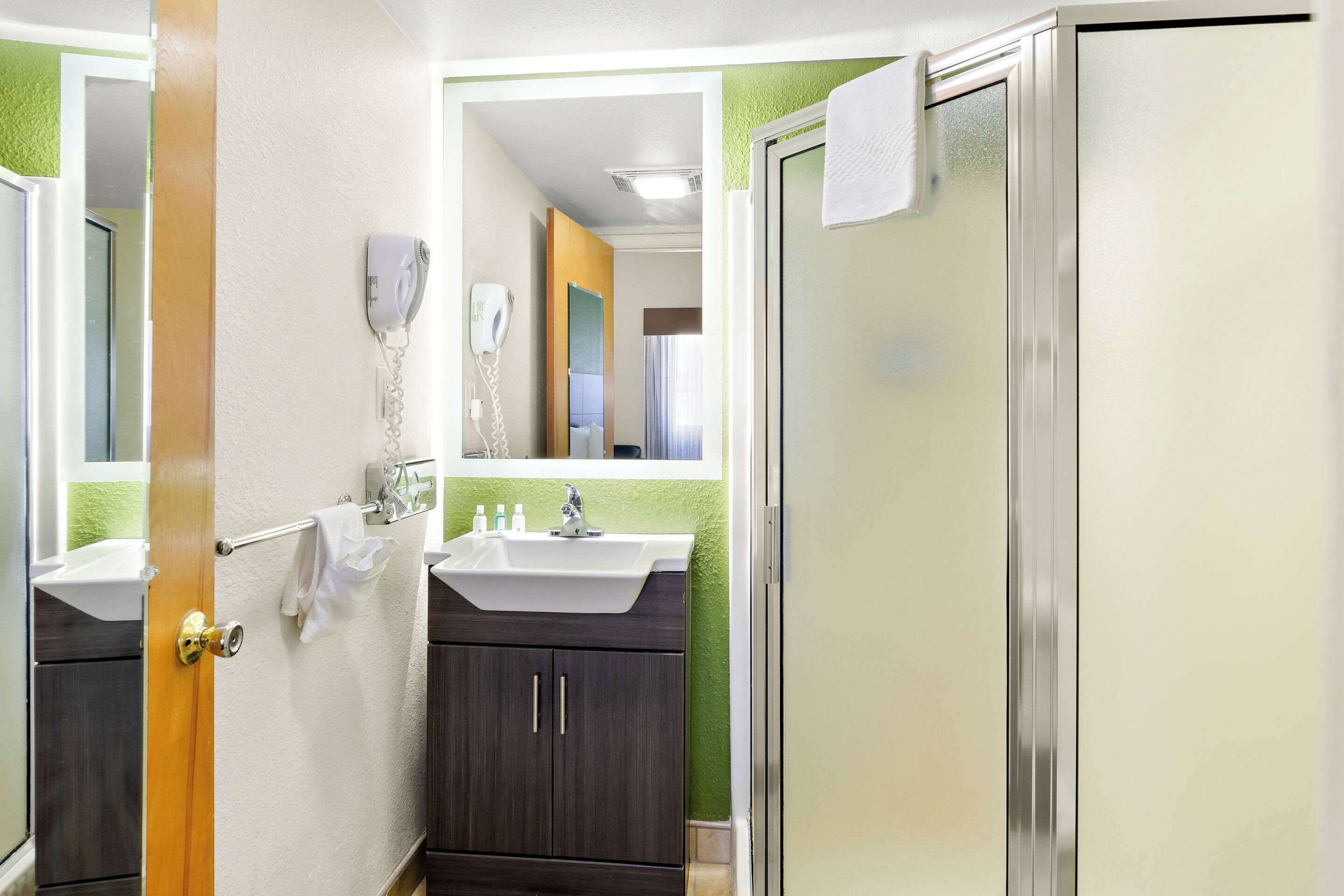 A bathroom with two sinks, a mirror, a towel rack, and a shower door.