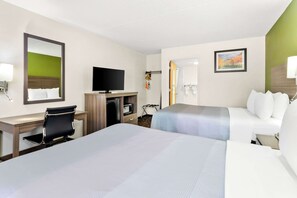 A hotel room with two beds, a desk with a chair, a television, a mirror, and a painting on the wall.