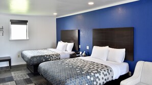 Habitación de hotel con dos camas, una mesita y una silla.