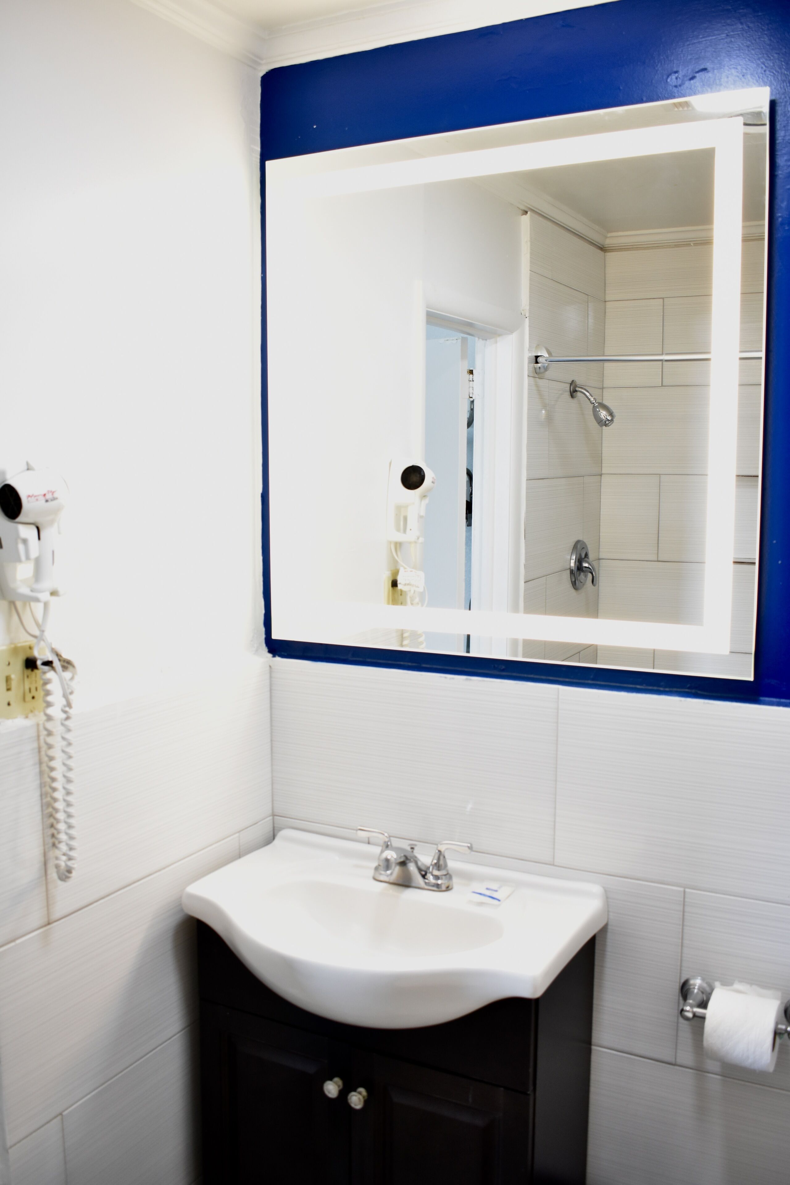 A bathroom with a white sink, a mirror, and a shower.
