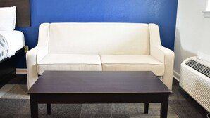 Una habitación con un sofá color beige frente a una pared azul, una mesa de madera oscura y un radiador blanco.