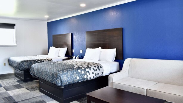 Habitación de hotel con dos camas, un sofá y una pequeña mesa.