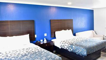 Una habitación de hotel con dos camas, una mesita de noche, una silla y una pared azul decorativa.