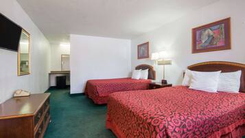 Une chambre d’hôtel avec deux lits, une commode, un bureau, une chaise et un téléviseur.