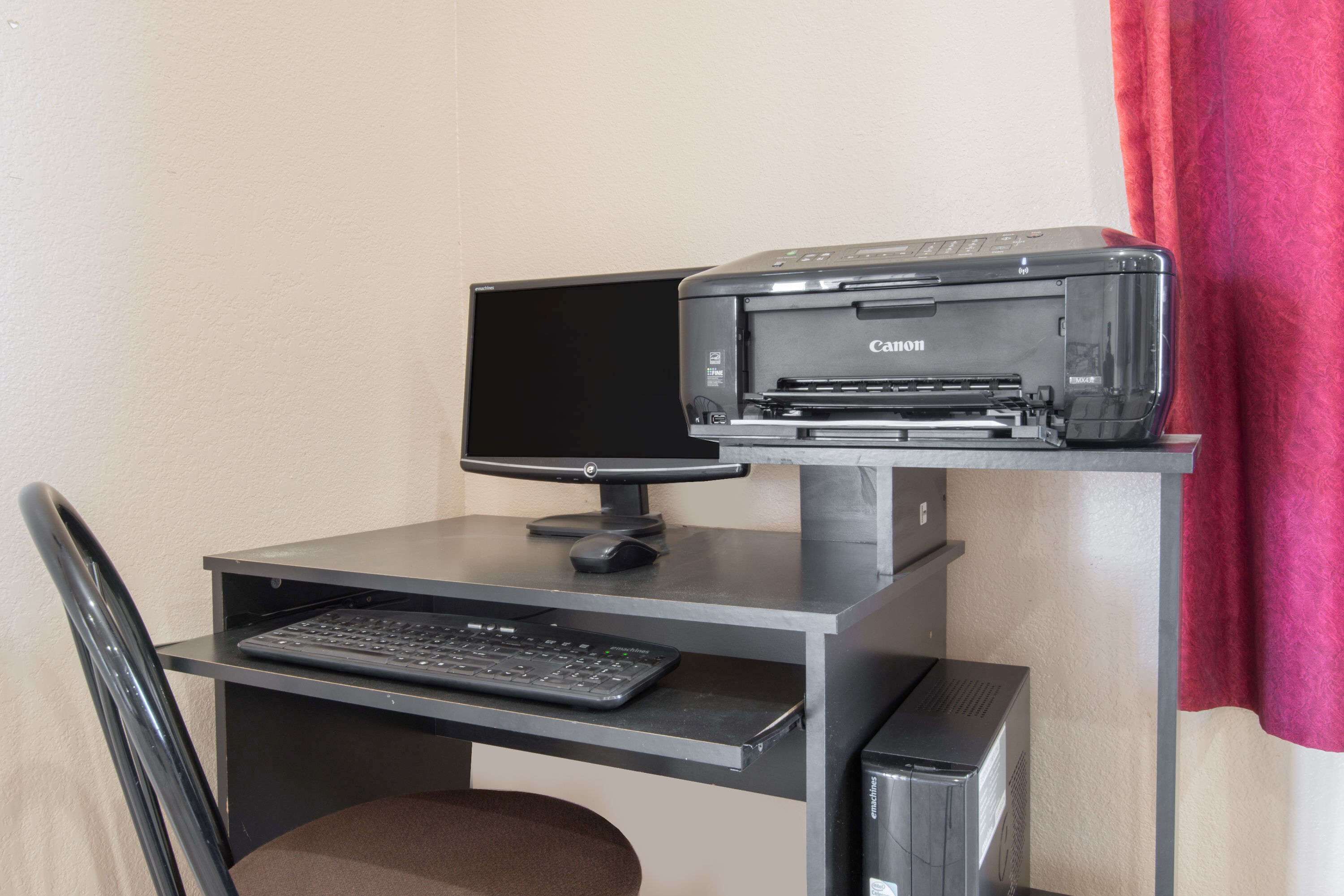 Un escritorio con un monitor, teclado e impresora.