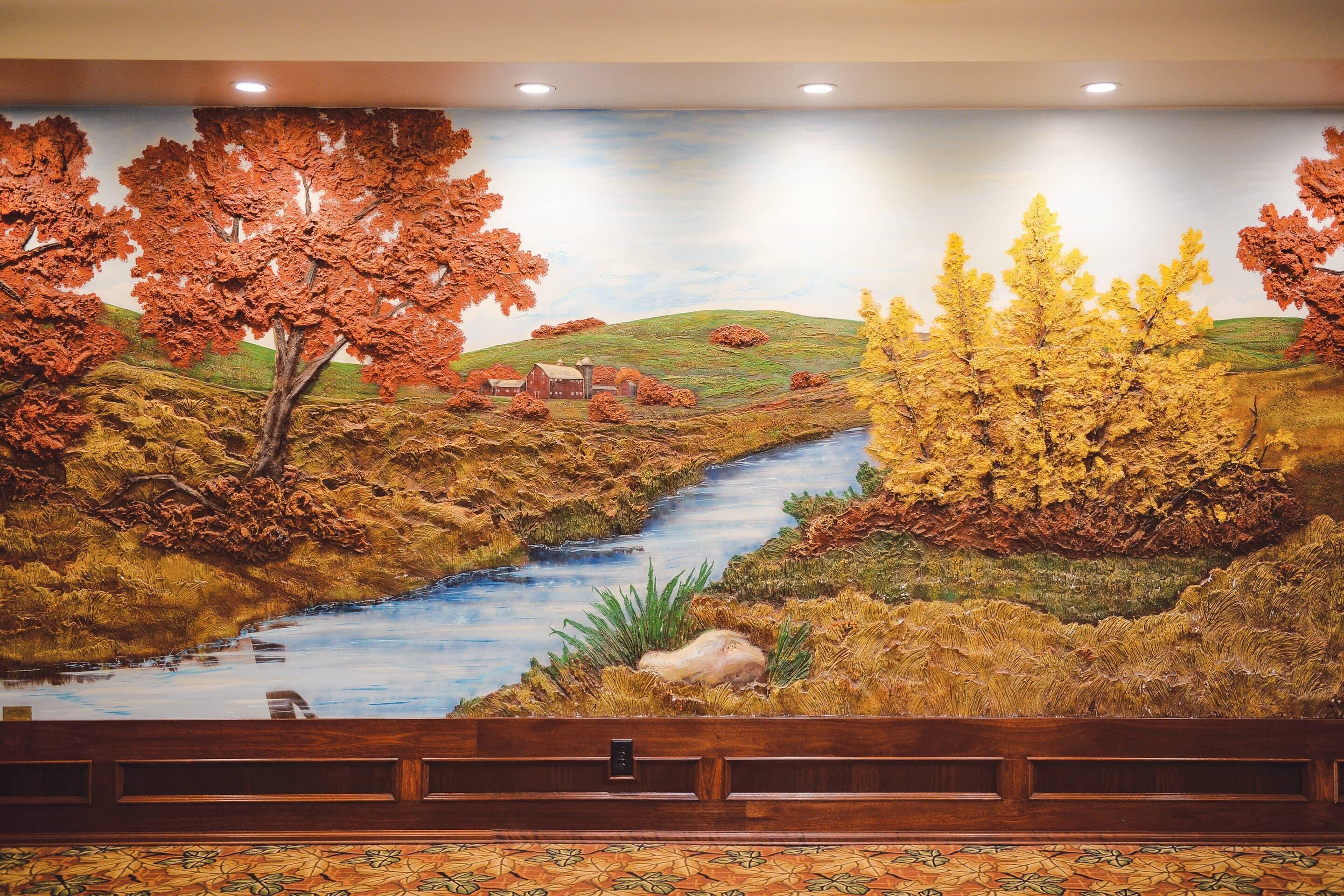 Un mural que muestra un río, árboles y un granero.