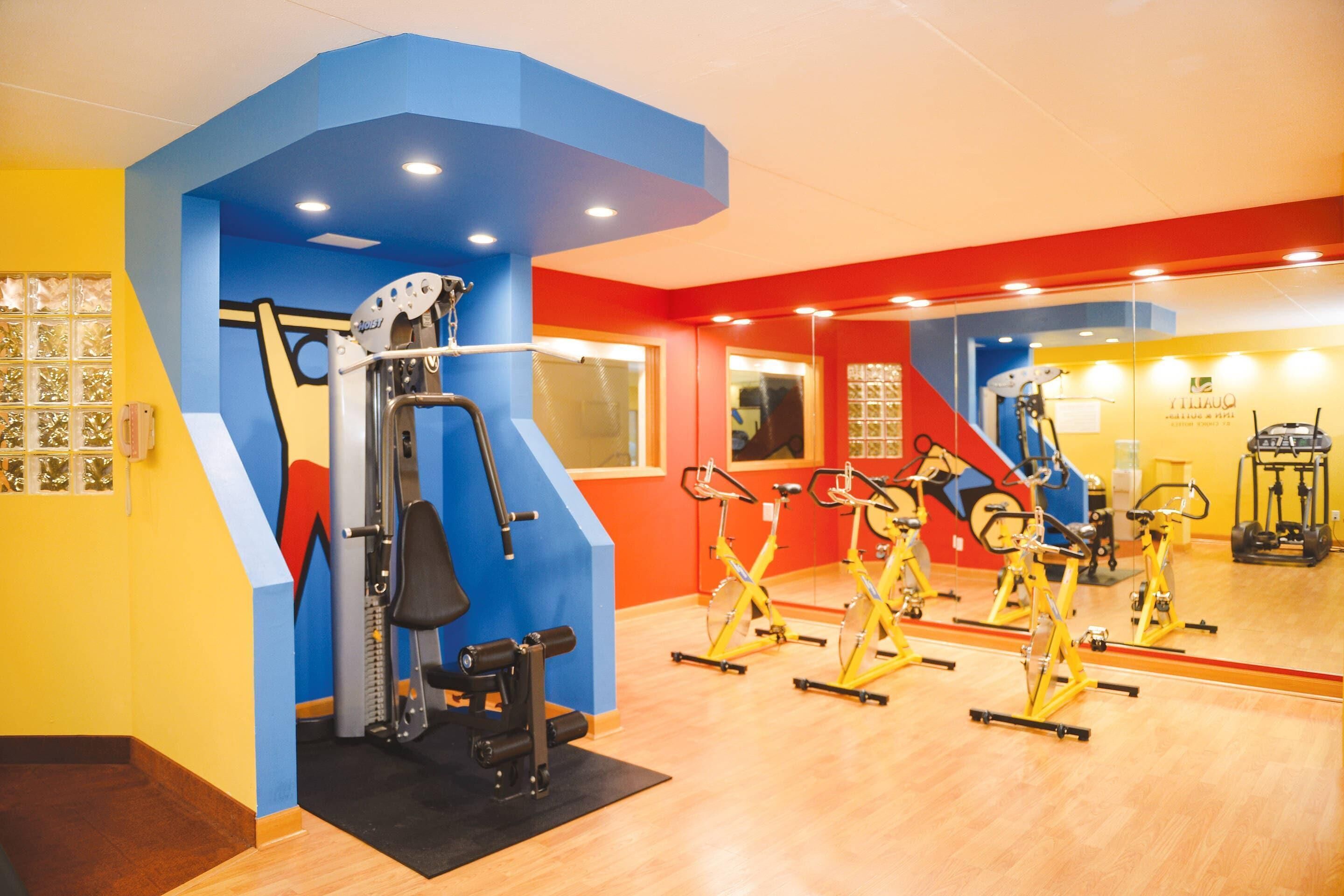 A gym with exercise equipment, including a weight machine and stationary bikes.