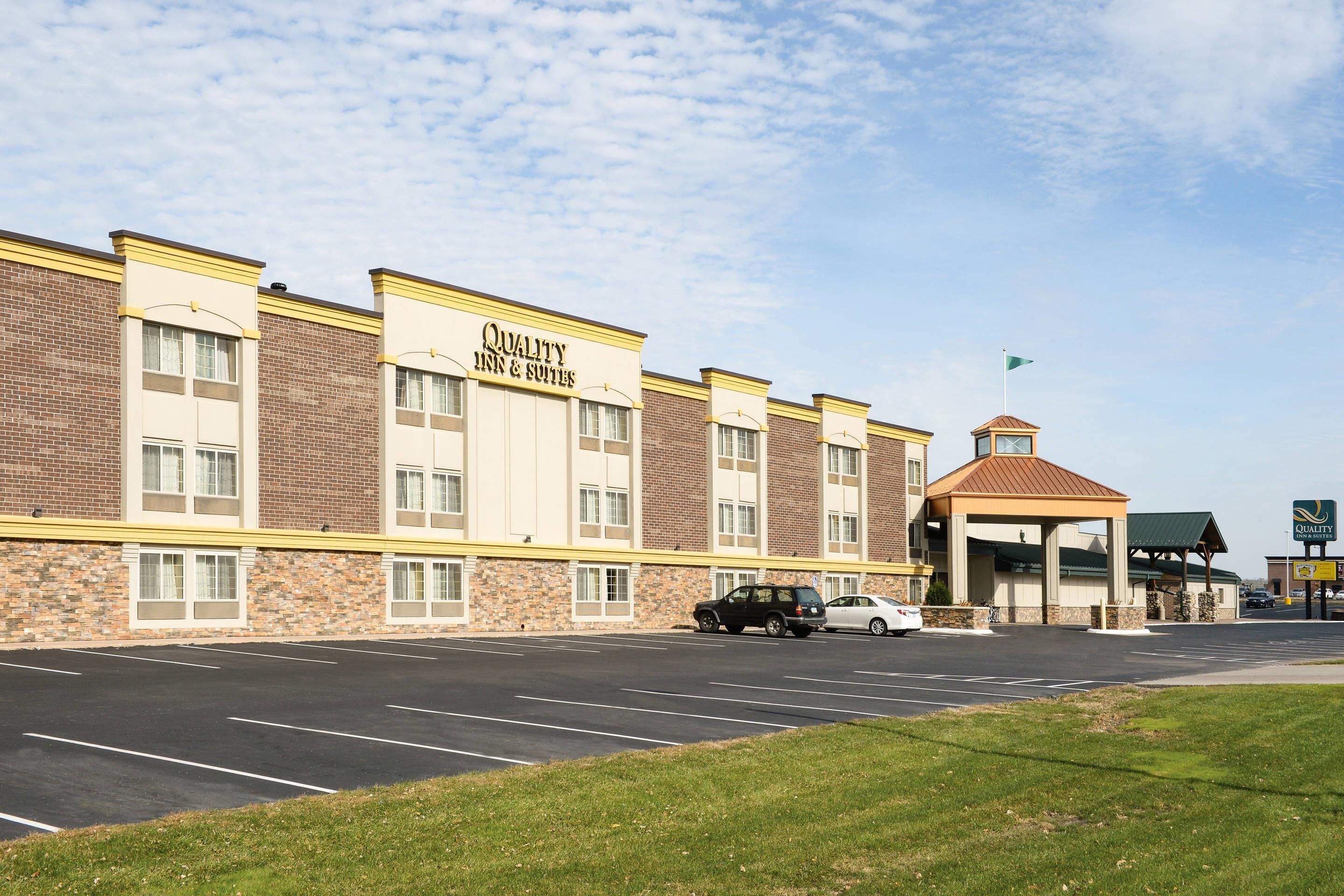 Un hotel con fachada de ladrillo, entrada cubierta y estacionamiento.