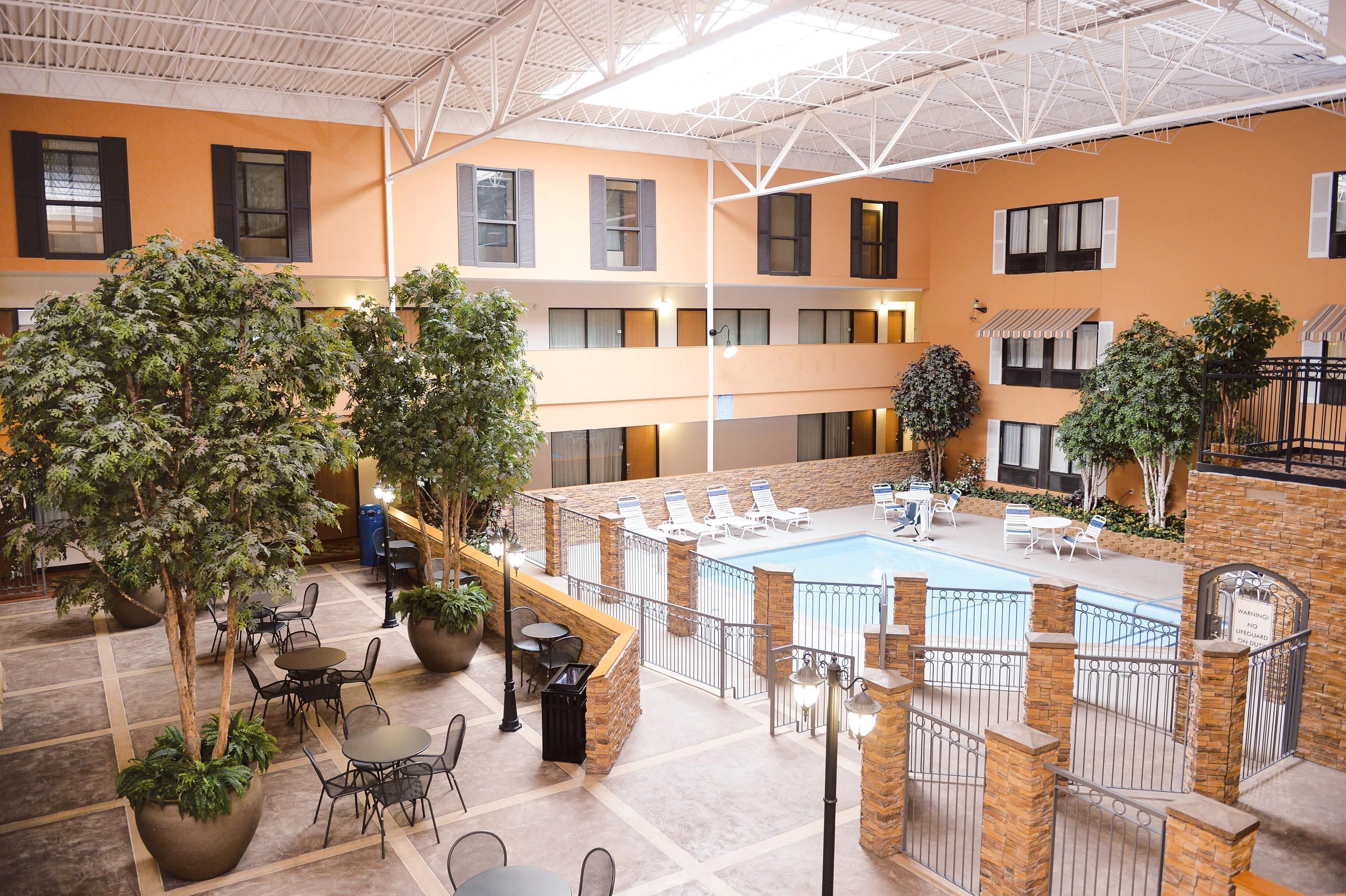 A multi-level indoor pool area with lounge chairs and potted plants.