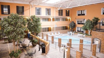A multi-level indoor pool area with lounge chairs and potted plants.