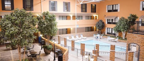 A multi-level indoor pool area with lounge chairs and potted plants.