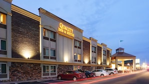 Un hotel llamado "Quality Inn & Suites" con fachada de ladrillo, múltiples ventanas y un área de entrada cubierta.