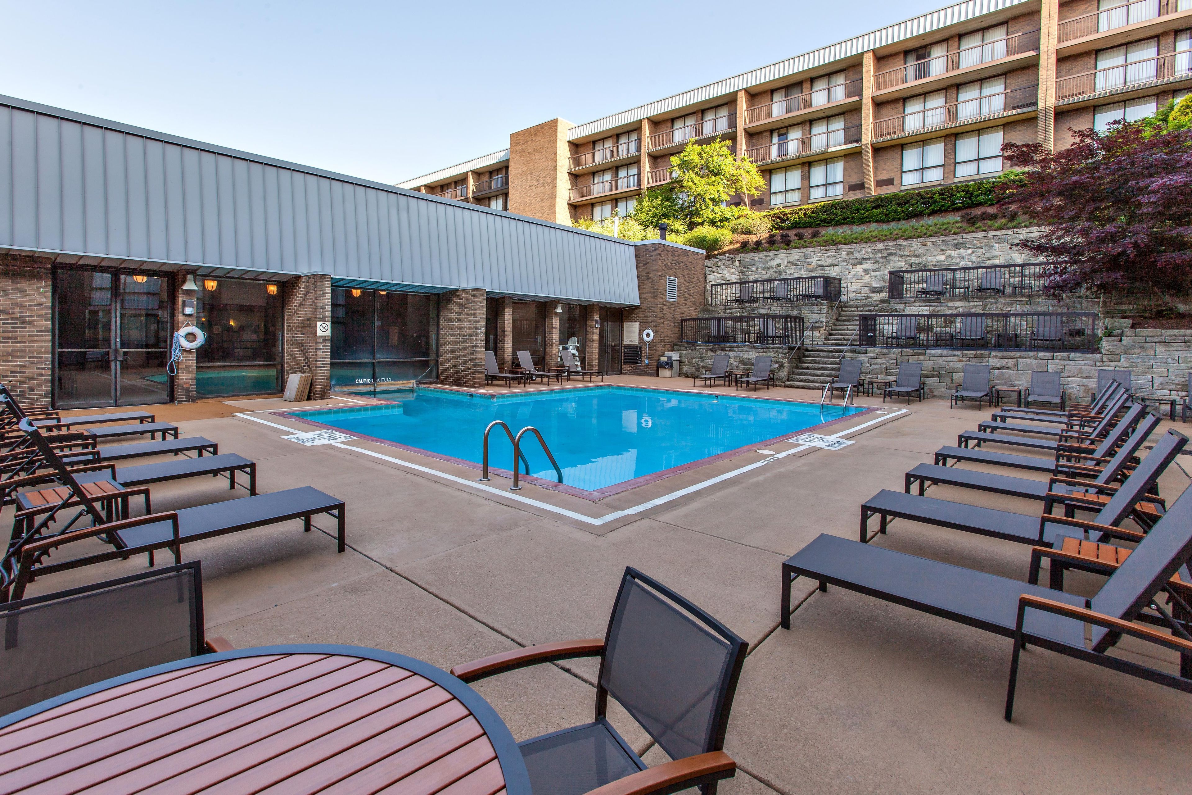 A pool area with lounge chairs and a building in the background.
