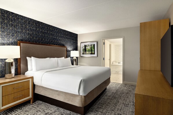 Habitación de hotel con una cama grande, mesitas de noche, un armario y un cuadro en la pared.