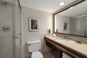 Un baño moderno con cabina de ducha de vidrio, inodoro blanco, tocador doble y un espejo grande.