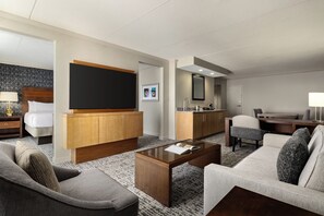 Una habitación de hotel con sala de estar, kitchenette, cama y baño.