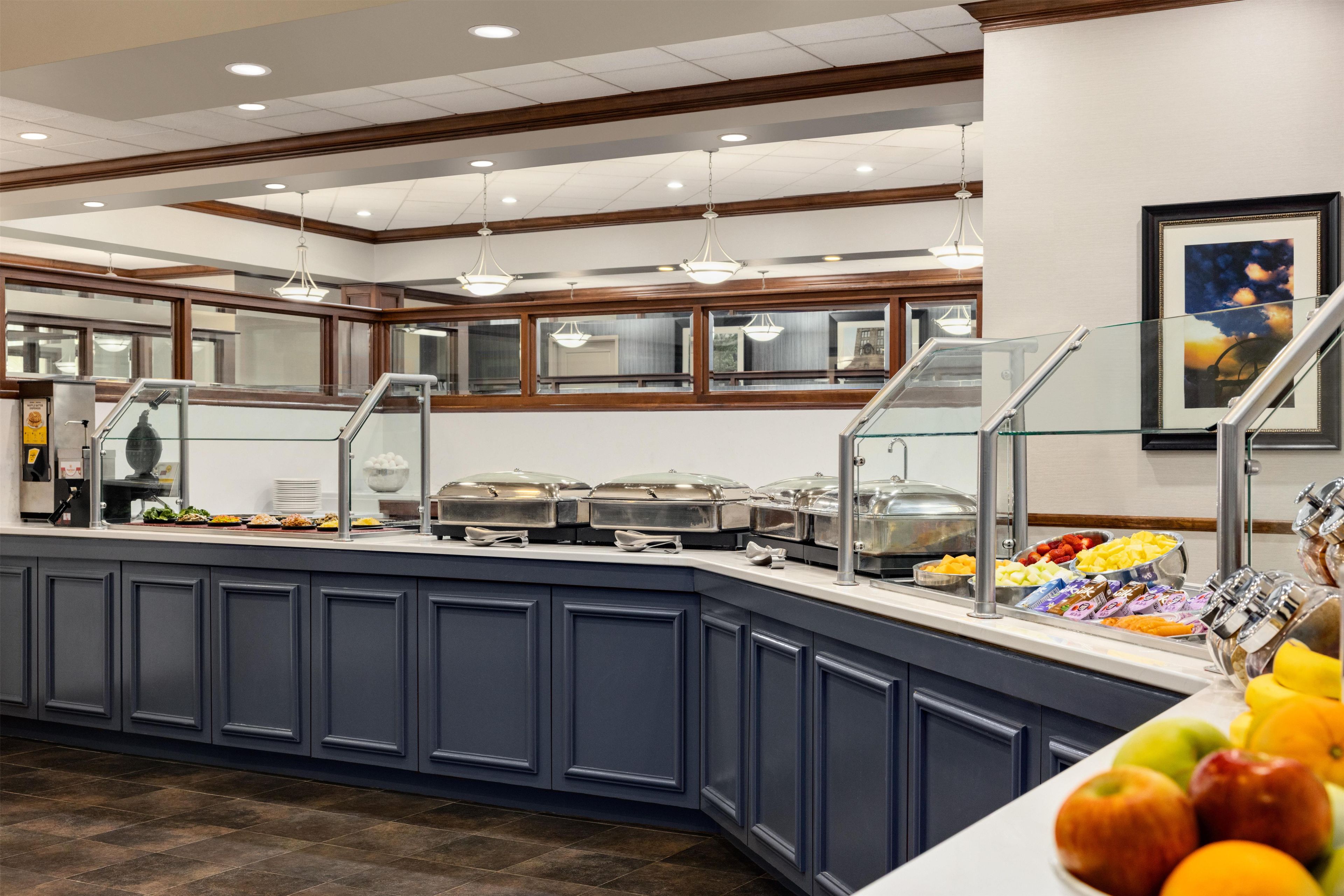A buffet area with a variety of food options, including fruits and dairy products, and a seating area with a view of the cityscape.