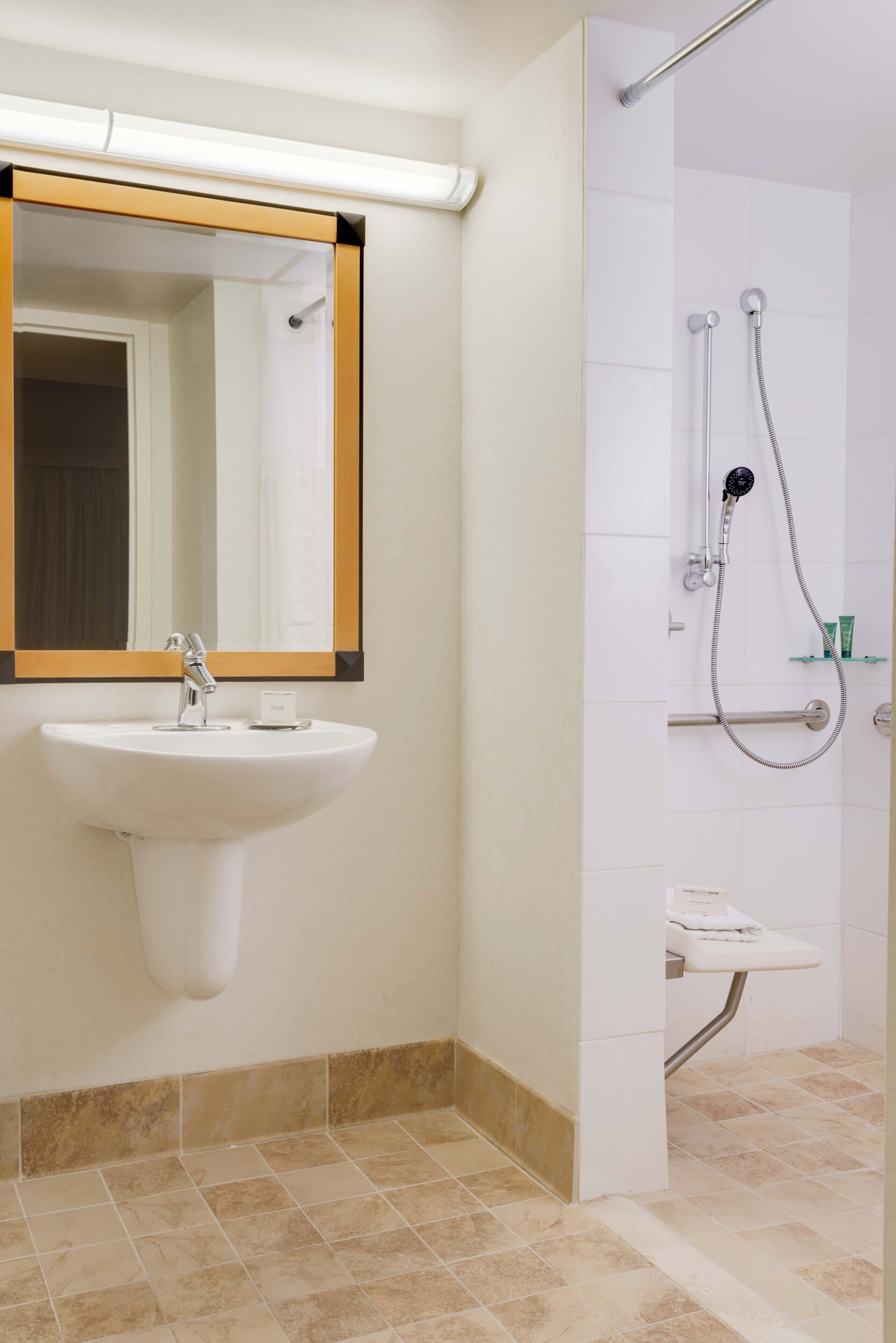 Un baño con lavamanos, espejo, ducha y perchero para toallas.