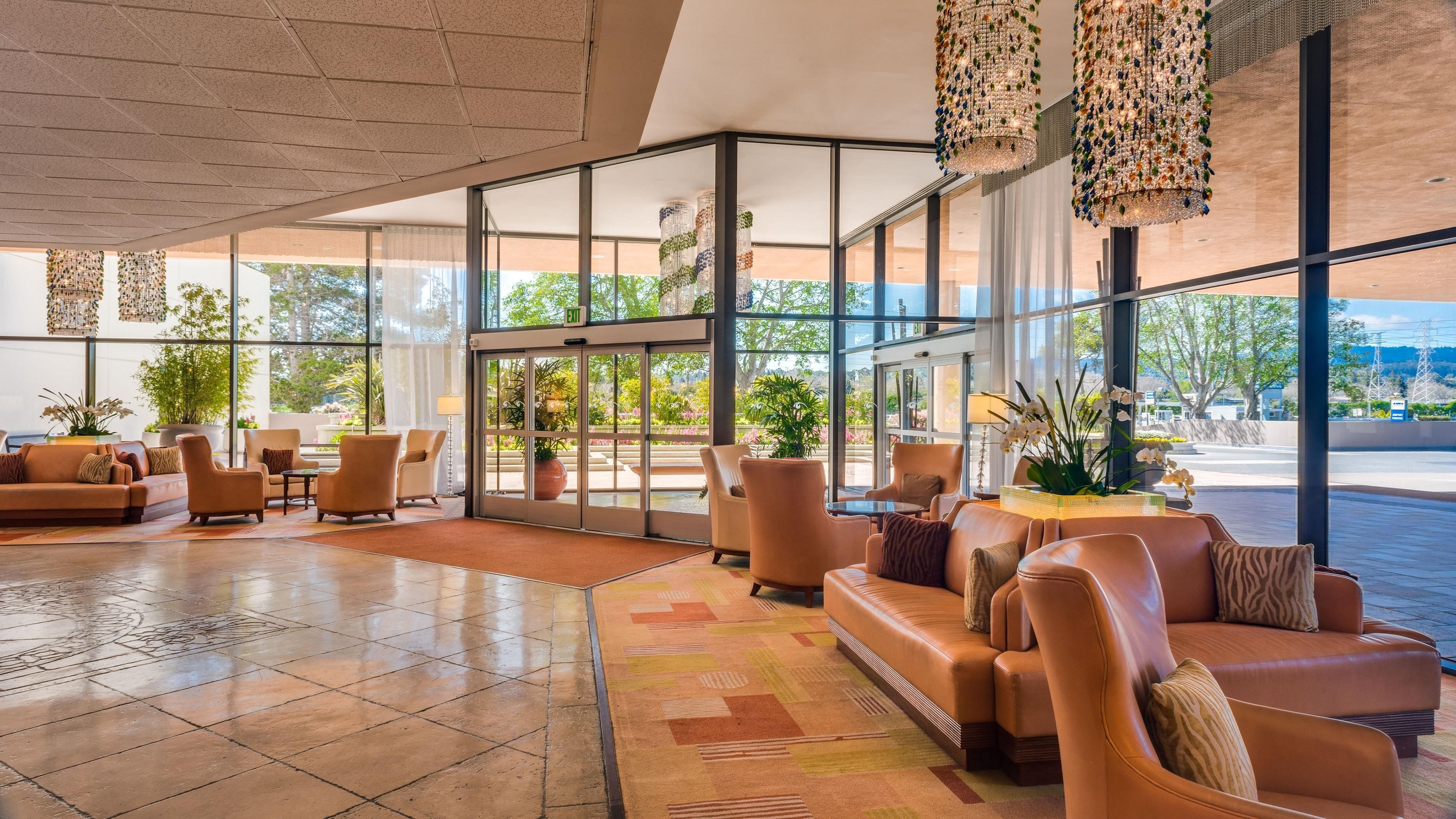 Un hall d’entrée spacieux, doté de canapés en cuir, d’un tapis à motifs et d’une entrée en verre.