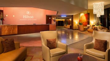A spacious lobby with a reception desk, leather armchairs, and a coffee table with a vase.