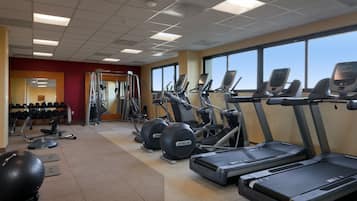 Uma academia com esteiras, elípticos e bolas de exercício.