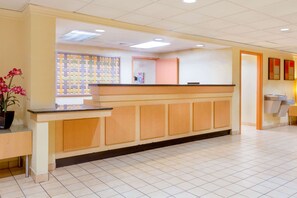 A reception area with a reception desk, a potted plant, and a tiled floor. - Spark by Hilton Charlotte Airport North (Charlotte)
