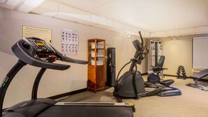 Un gimnasio con cintas de correr, elíptica y máquinas de pesas.