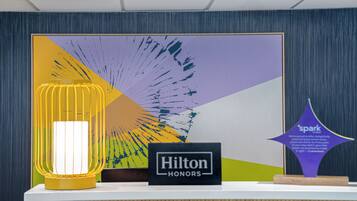 A reception desk with a framed artwork, a sign reading 'Hilton HONORS', and a 'spark' award plaque.