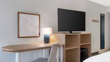 Hotellihuone, jossa on työpöytä, tuoli, televisio ja sänky.