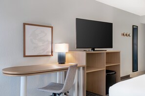 Habitación de hotel con escritorio, silla, televisión y cama.