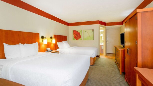 Habitación de hotel con dos camas, televisor, escritorio y armario.