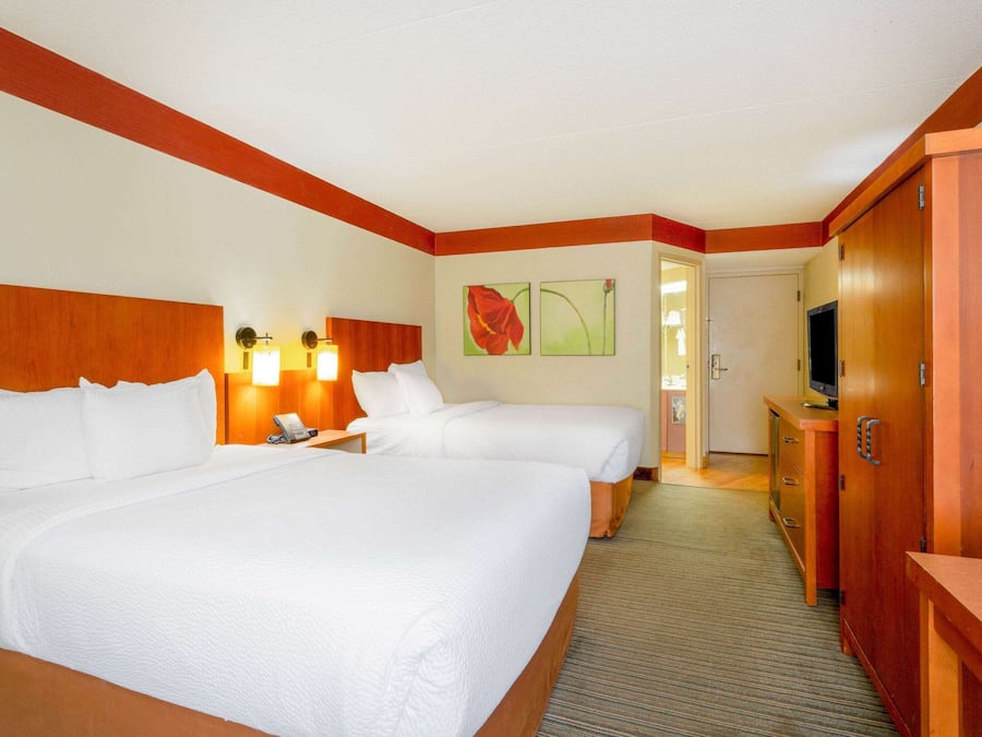 A hotel room with two beds, a TV, a desk, and a wardrobe.