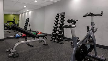 A gym with exercise equipment, a bench, and a mirror.