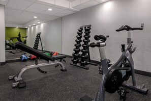 A gym with exercise equipment, a bench, and a mirror.