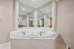 Un baño con una bañera independiente grande, un lavabo doble y un espejo sobre la bañera.