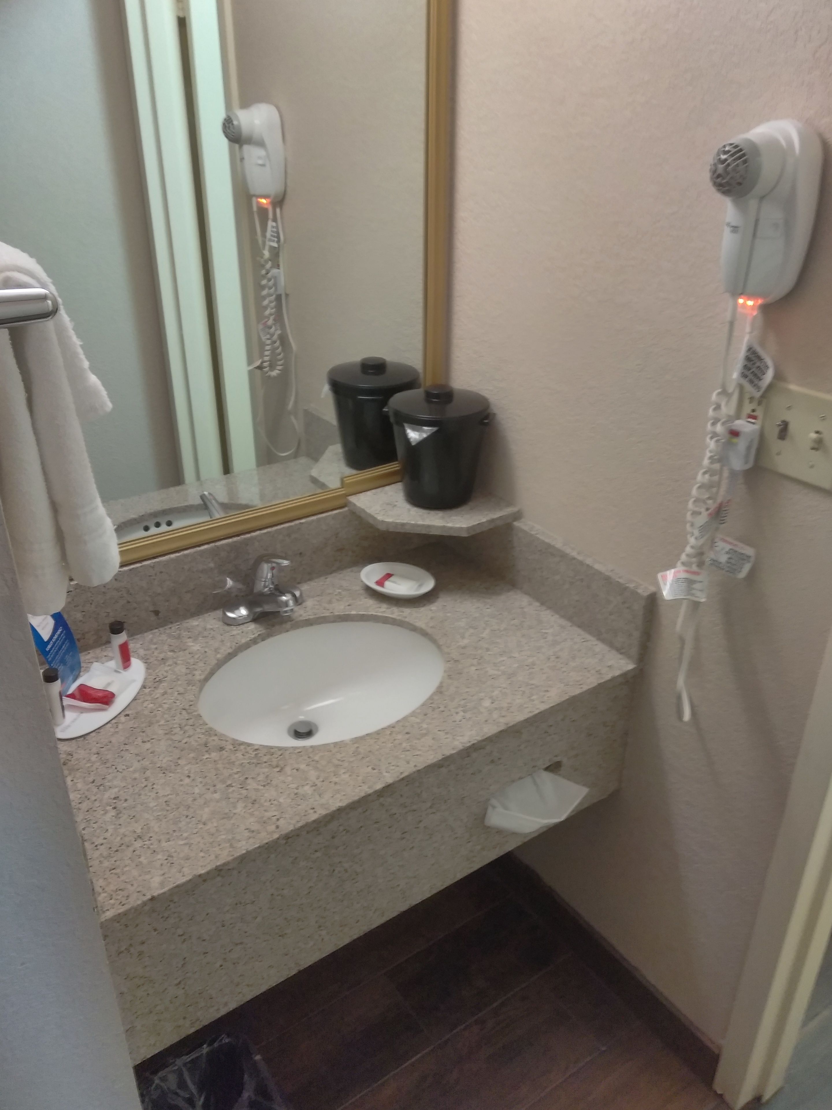 Une salle de bain équipée d’un lavabo, d’un miroir, d’un sèche-cheveux et d’articles de toilette.