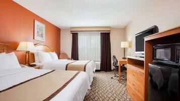 A hotel room with two beds, a desk, a television, and a dresser.