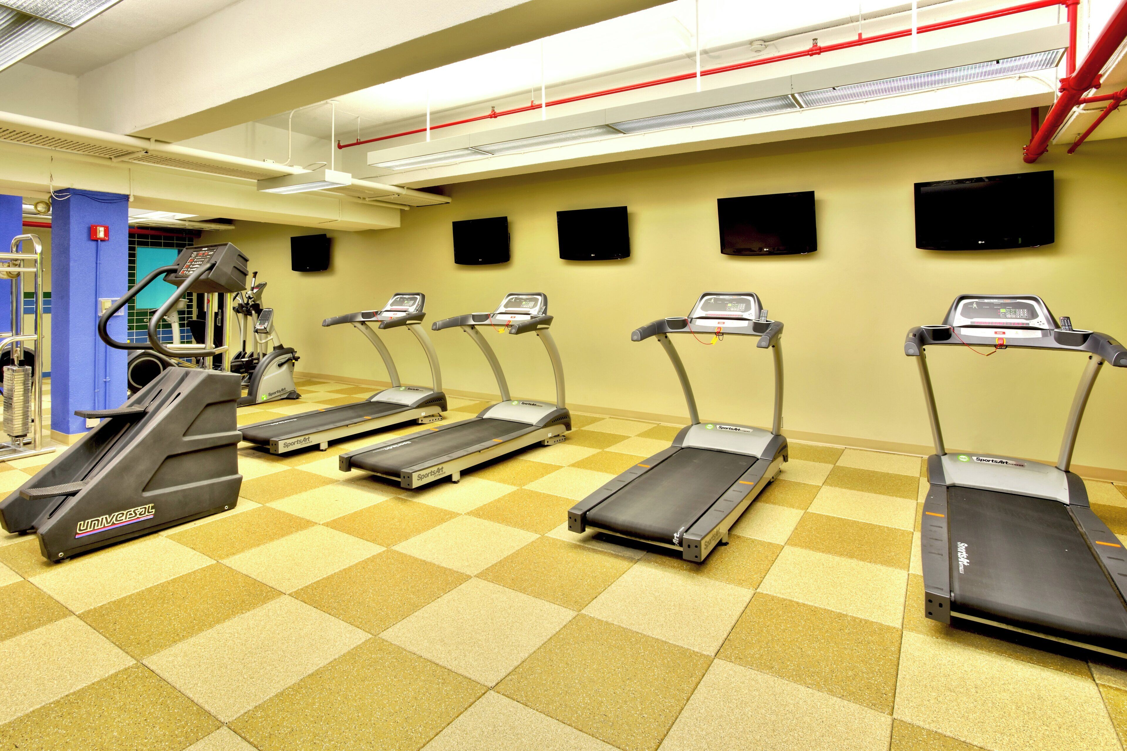 Un gimnasio con cintas de correr, una bicicleta estática y una máquina de escaleras.