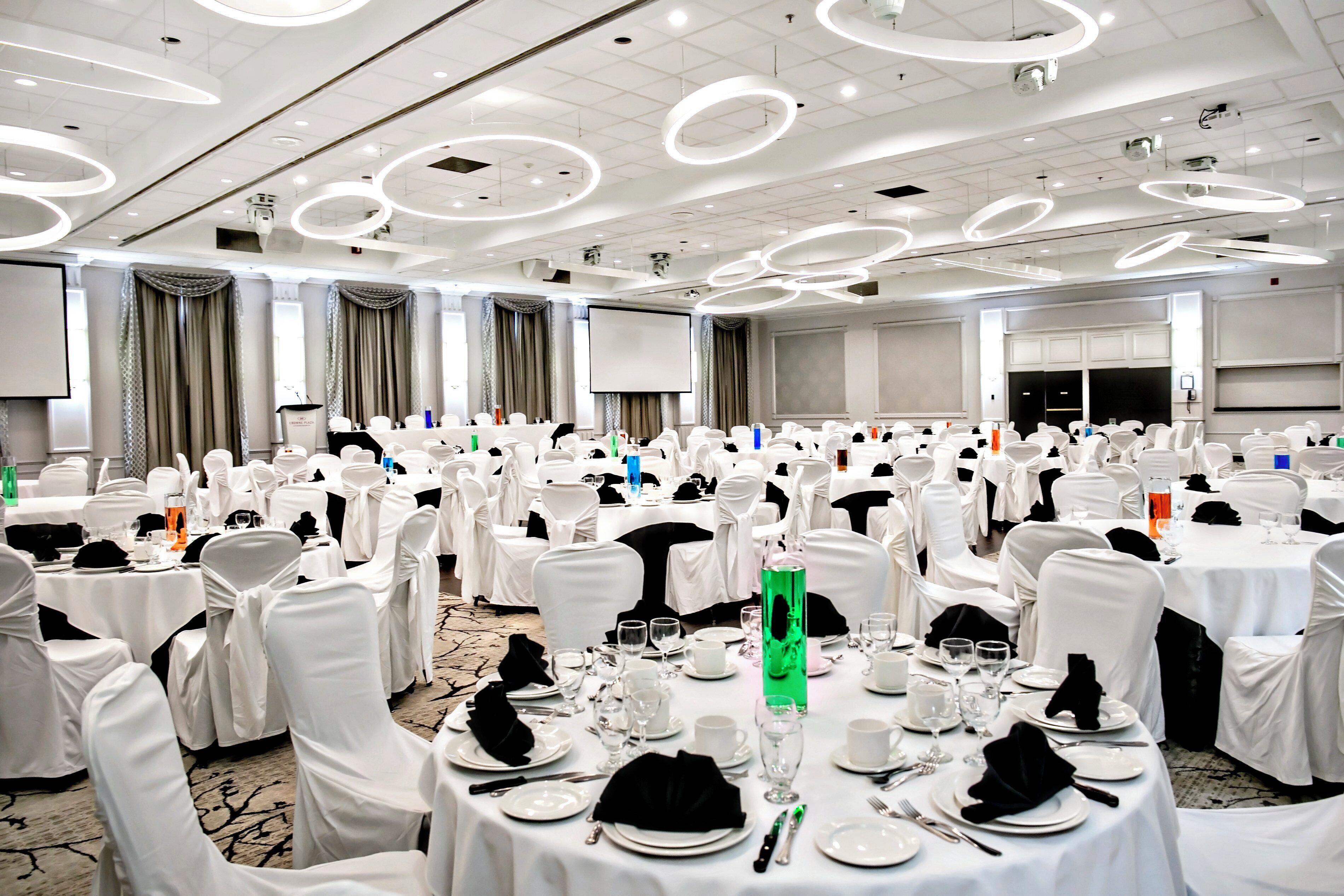 A large conference room with round tables, white chairs, and a modern ceiling design.