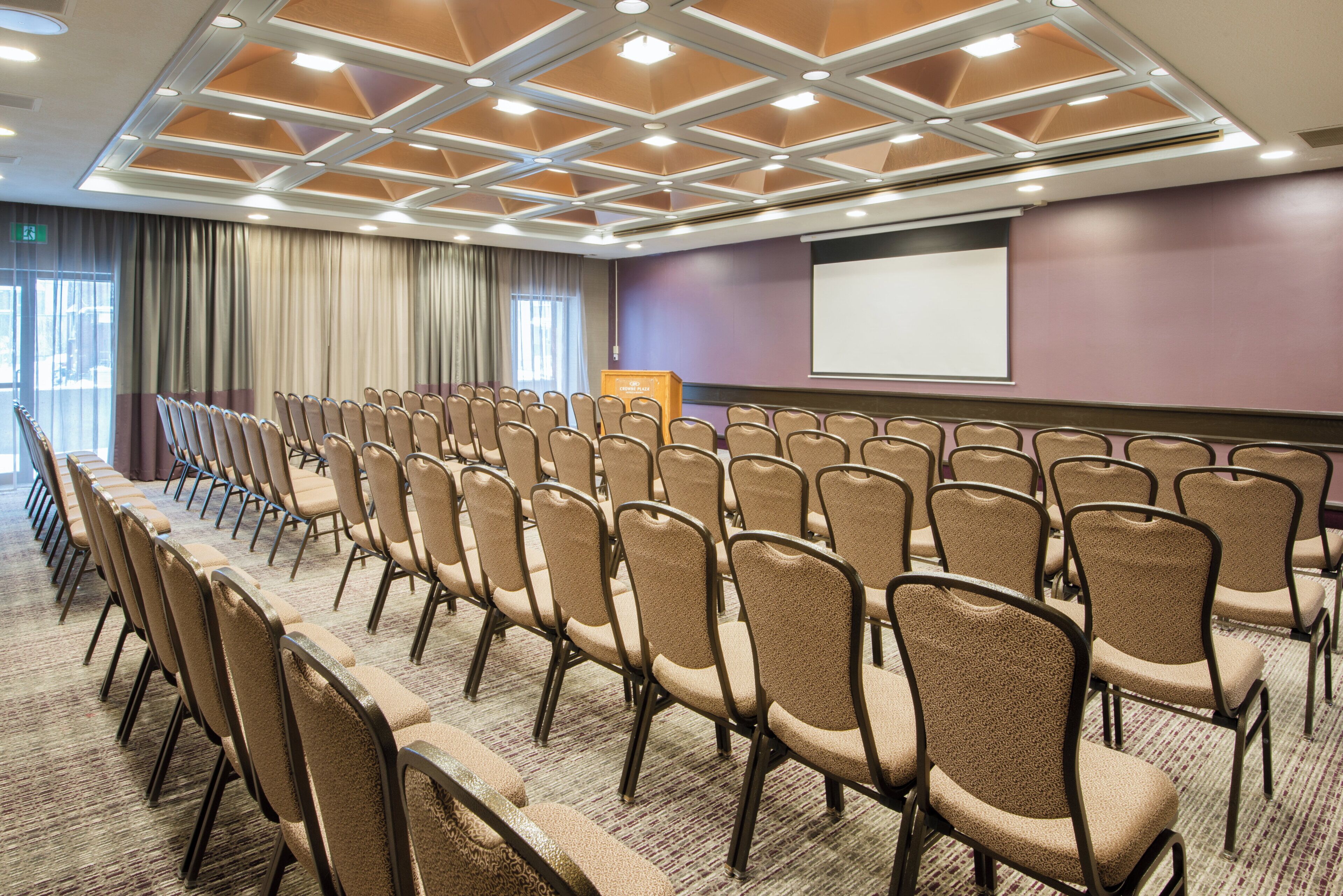 A conference room with rows of chairs, a projector screen, and a podium.