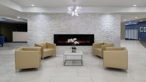 A modern lobby with a stone wall, a fireplace, and two beige sofas around a glass coffee table. - Crowne Plaza Kitchener-Waterloo by IHG (Kitchener)