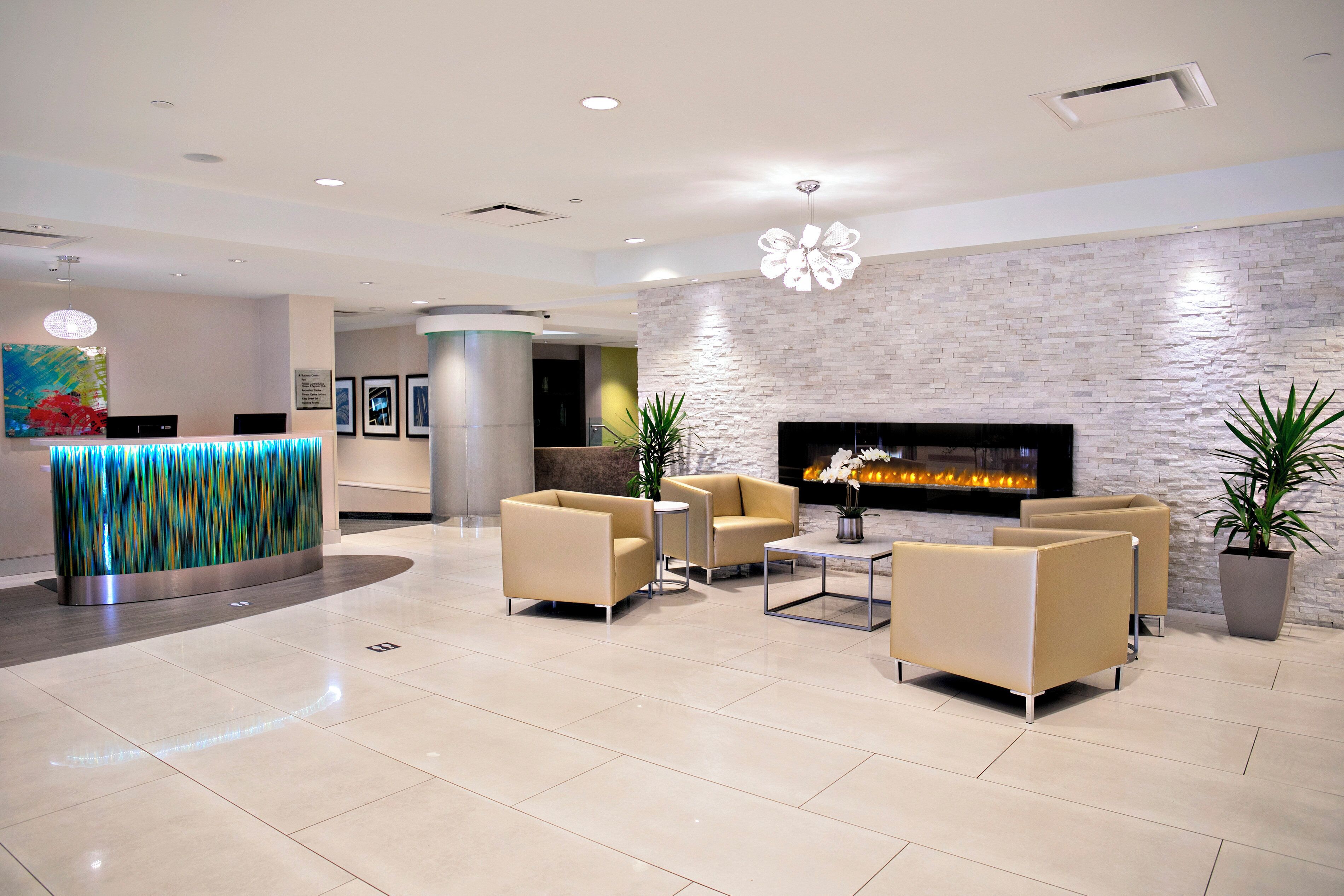 A modern lobby with a reception desk, seating area, and a fireplace.