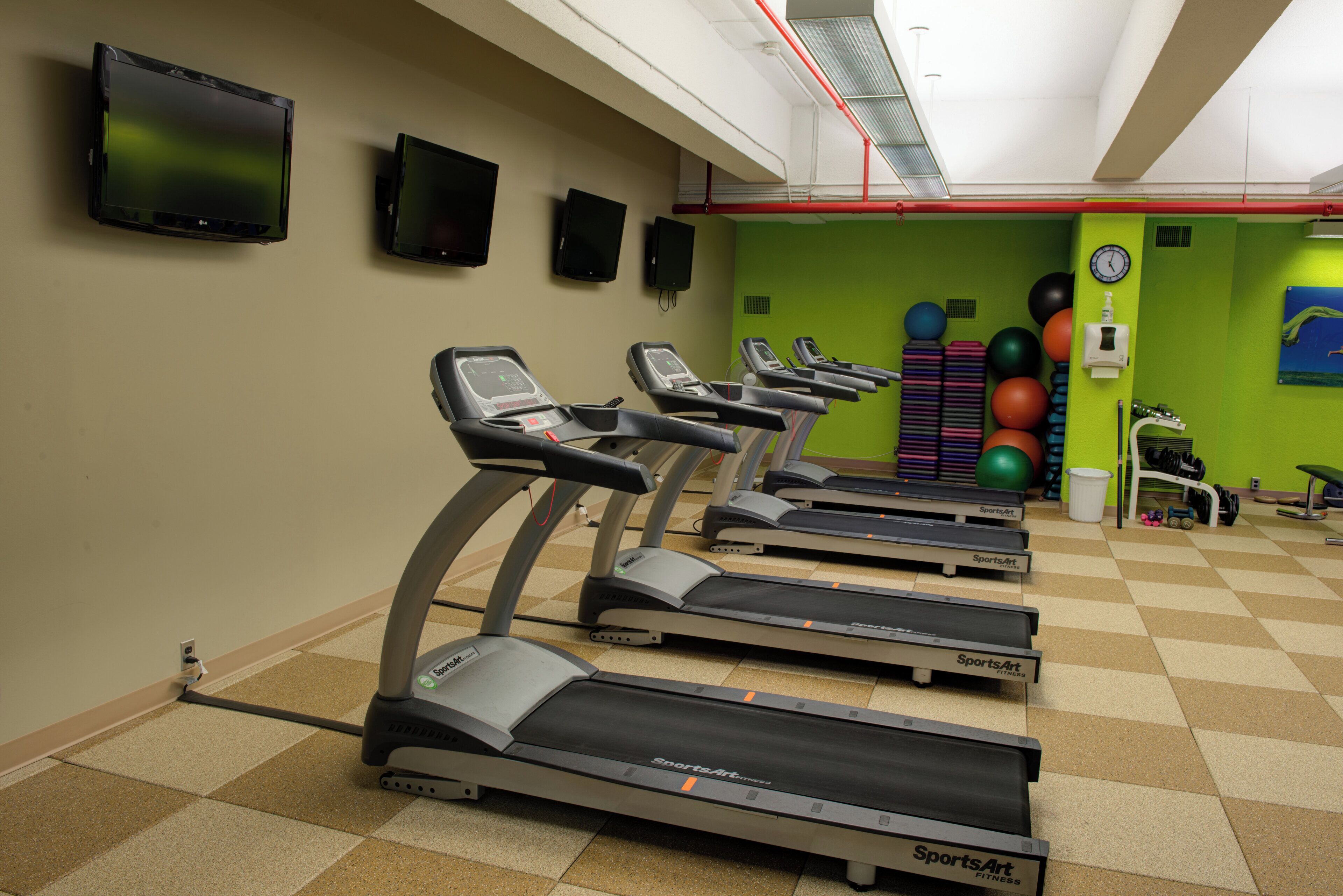 Una palestra attrezzata con tapis roulant, palle da ginnastica e manubri.