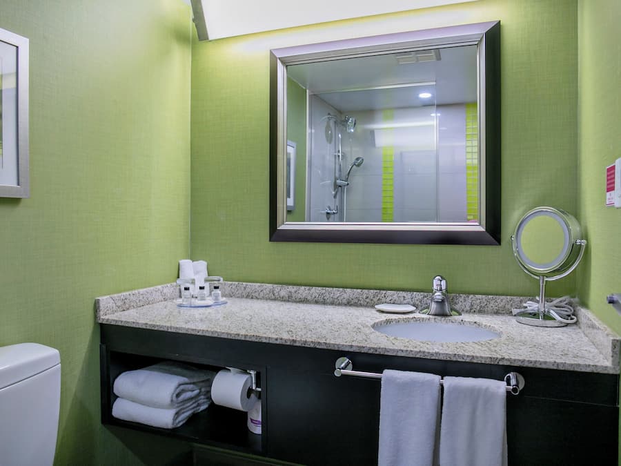 Un baño con lavamanos, espejo, toallero y retrete.