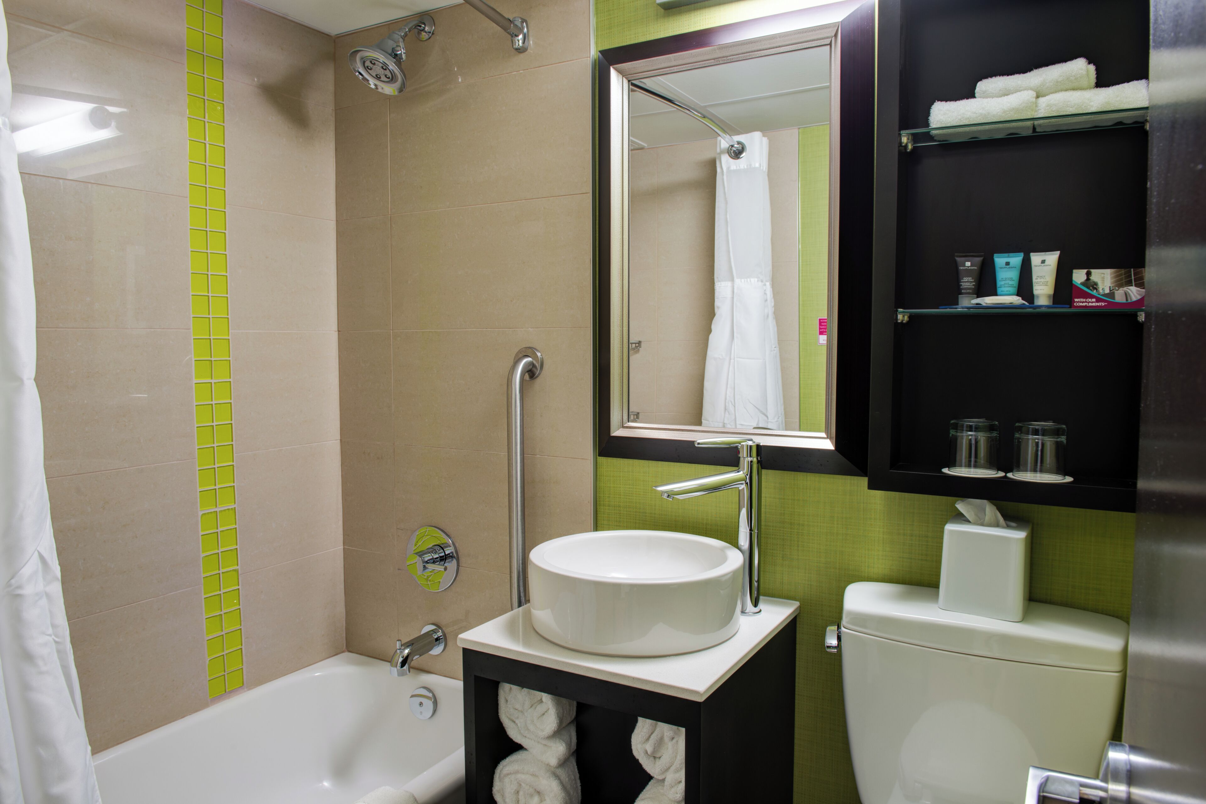 A bathroom with a bathtub, a sink, a toilet, and a mirror.